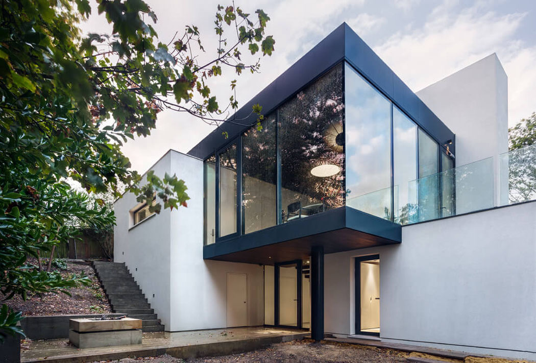 Maison contemporaine blanche avec volume vitré en encorbellement, vue depuis le jardin
